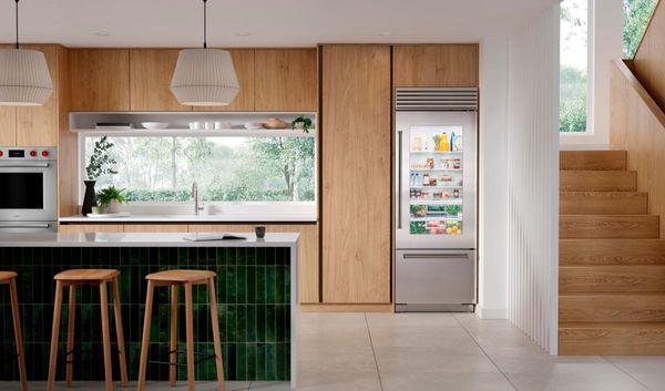 front view of a modern kitchen with a narrow bottom freezer refrigerator built into wooden cabinetry