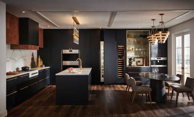 front view of a double wall oven built into a contemporary kitchen with black cabinetry and panel ready appliances with gold accents
