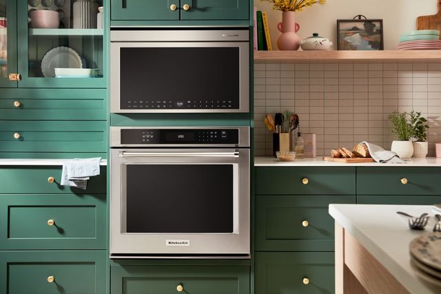 Credit: KitchenAid Front view of a modern kitchen with green cabinetry and a built in microwave and oven from KitchenAid