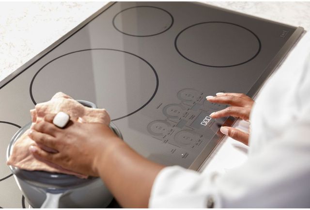 View of a person pressing the touch controls on a Cafe 36 in induction cooktop
