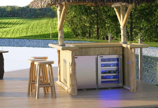 front view of a small tiki bar in front of a waterfront with two stainless steel perlick refrigerators behind it