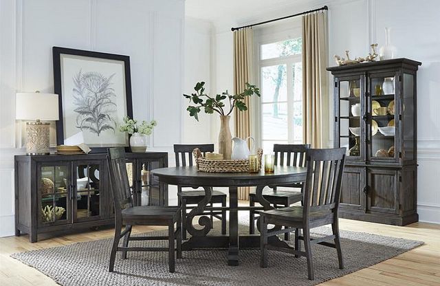 front view of a casual dining room with white walls and dark furniture including a round table, classic dining hutch and matching sideboard