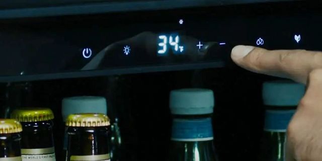 front view of a person setting the temperature on a mini beverage fridge