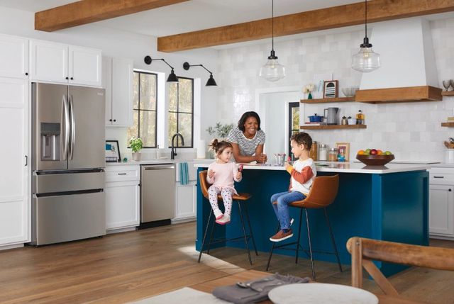 Credit: Frigidaire Front view of a modern kitchen with a mother and two children sitting at an island near a Frigidaire dishwasher and refrigerator