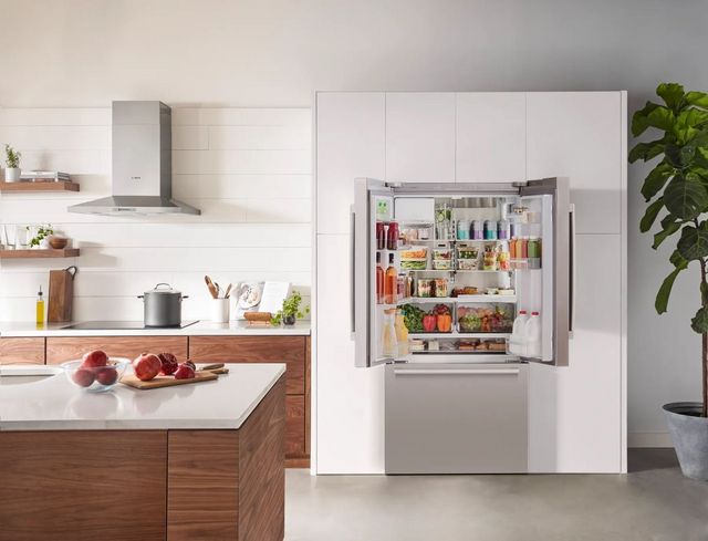 Front view of a modern kitchen with an open Bosch refrigerator opened and stocked.