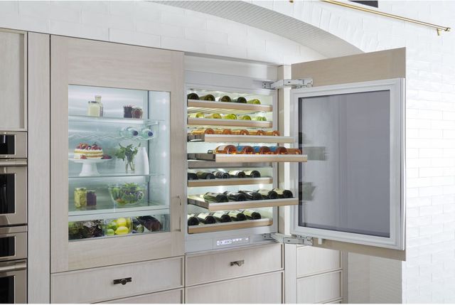 Front view of a panel ready wine refrigerator opened with a wine drawer pulled out built in to a modern kitchen.