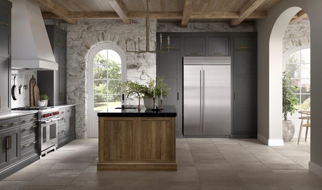 Front view of a rustic kitchen with grey cabinetry and a counter depth Sub-Zero refrigerator