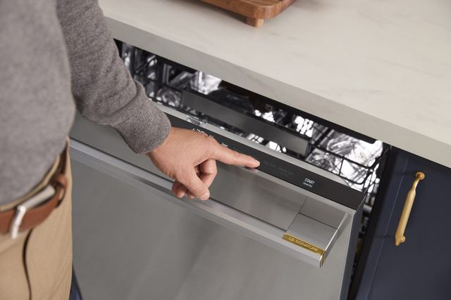 Front view of a modern kitchen as a person closes an LG Signature dishwasher Front view of a modern kitchen as a person closes an LG Signature dishwasher