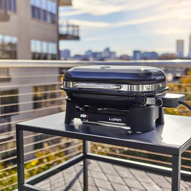 Front view of a modern outdoor patio and balcony with a portable grill on the table