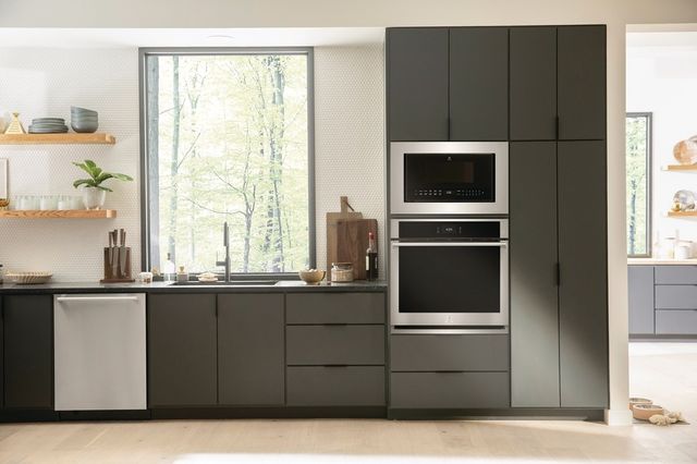 front view of a modern kitchen with dark grey cabinets and a built in microwave