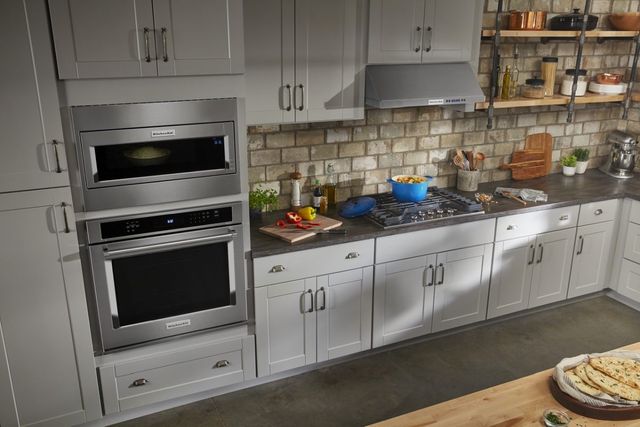 view of a modern kitchen with kitchen with white cabinets and a built in microwave over a built in wall oven