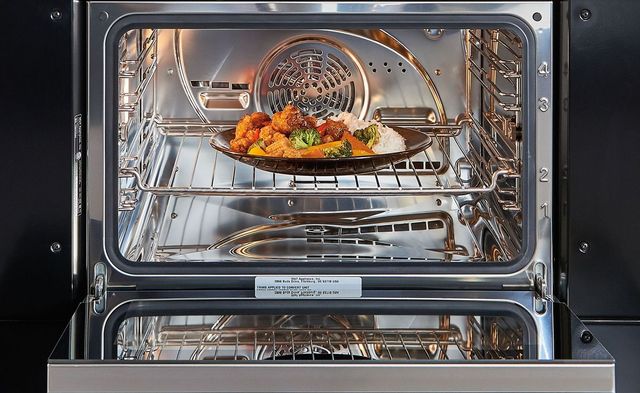 front view of the inside of a steam oven with veggies cooking inside