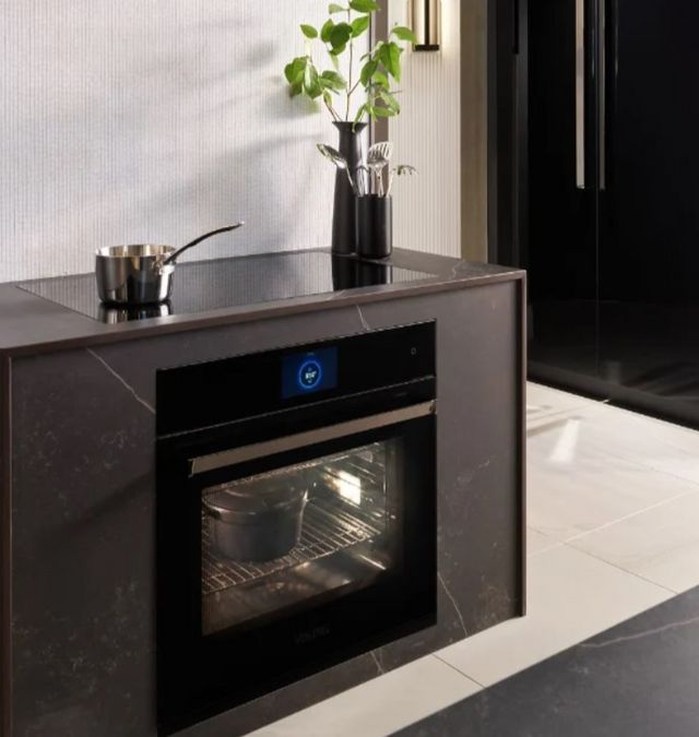 Front view of a contemporary kitchen island with a Viking wall oven under a cooktop
