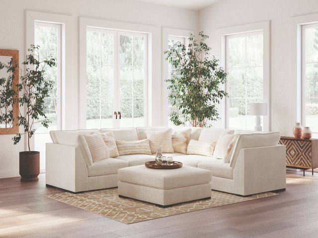 Front view of a modern living room with a Benchcraft sectional sofa and ottoman.