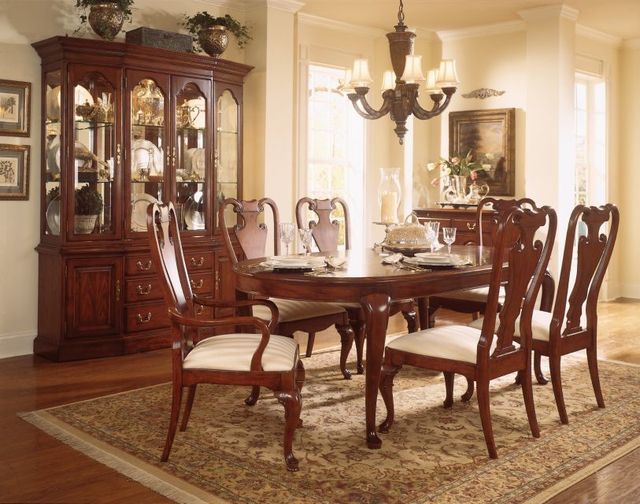 front view of a traditional dining room with beige walls, a wooden table and chairs, and a matching display cabinet