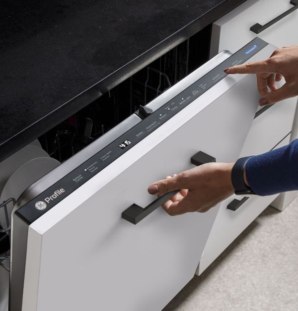 A black GE Profile built-in dishwasher installed in a modern kitchen with dark cabinetry
