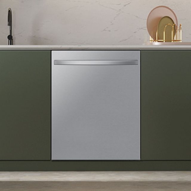 front view of a stainless steel samsung dishwasher built into a modern green cabinet