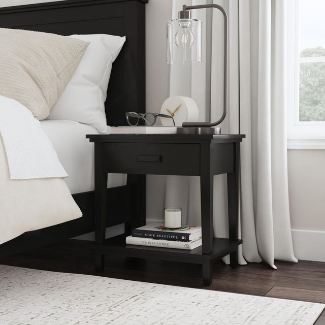 front view of a black nightstand next to a black bed frame in a modern bedroom