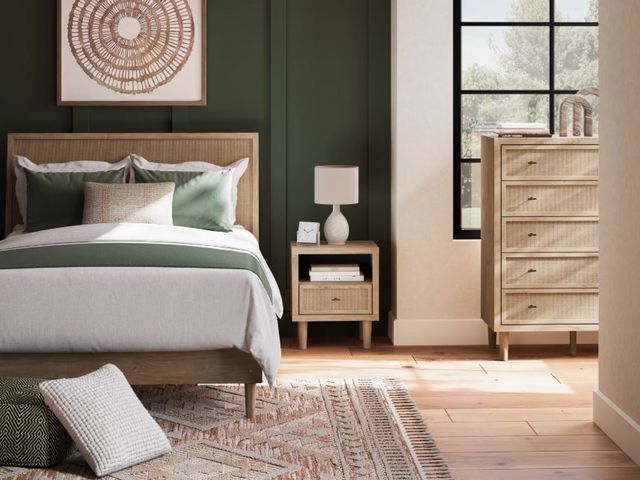 Front view of a casual bedroom with a mattress on a platform bed and matching light wooden furniture.