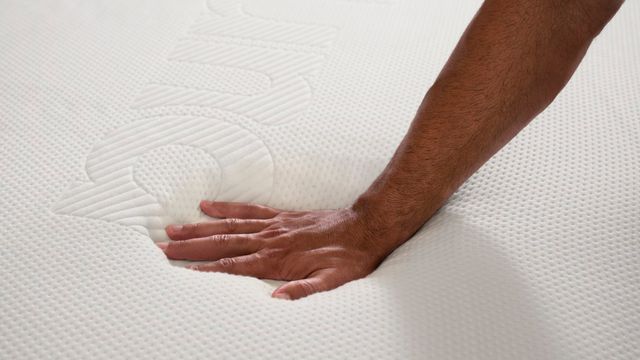 Close view of a person pressing their hand on a Purple mattress