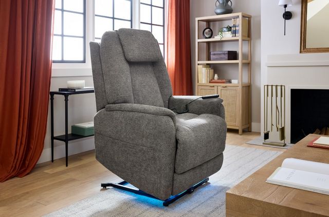 View of a Flexsteel lift recliner chair with a blue led light underneath in a modern living room with red curtains and white walls.