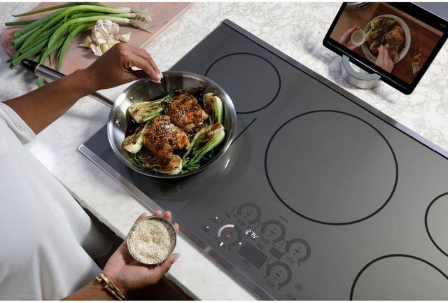 Top view of a person cooking on a Cafe induction cooktop and following a recipe