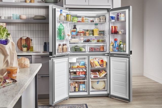 Front view of an opened and stocked Whirlpool four door french door refrigerator.