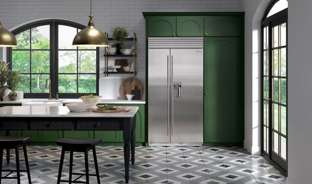 Front view of a modern kitchen with green cabinetry and a side-by-side built in Sub-Zero refrigerator