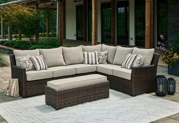 Front view of the Signature Design by Ashley® Brook Ranch 3-Piece Beige/Brown Outdoor Fabric/Wicker Sofa Sectional and Bench in a modern patio