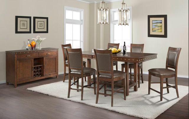 front view of a wooden pedestal dining table with six matching chairs around it and a sideboard in the background