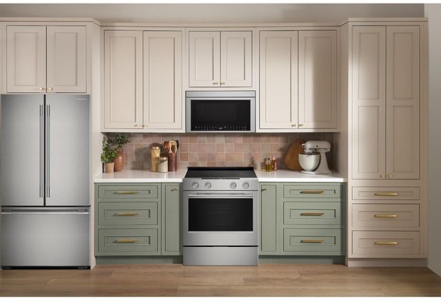 Front view of a modern kitchen with a KitchenAid electric range, over the range microwave, and refrigerator