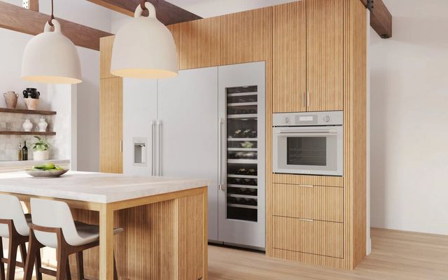 front view of a modern kitchen with a thermador speed oven, wine cooler, and refrigerator built into wooden cabinetry