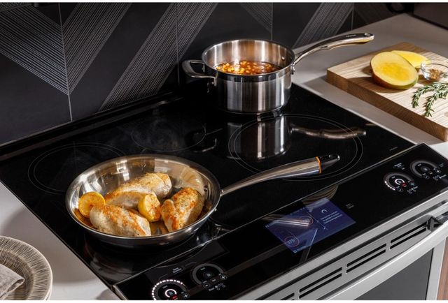 View of a GE Profile induction cooktop with foods cooking in pots and pans on top
