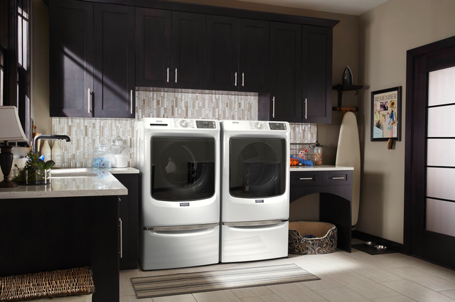 Front view of a modern laundry room with a Maytag front load washer and dryer set
