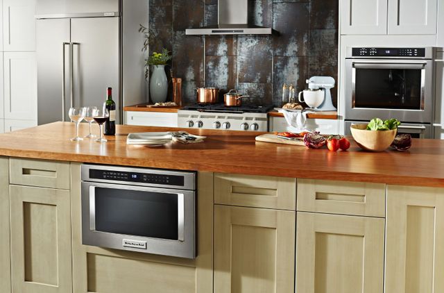 front view of a modern kitchen with a stainless steel microwave drawer built into the cabinetry