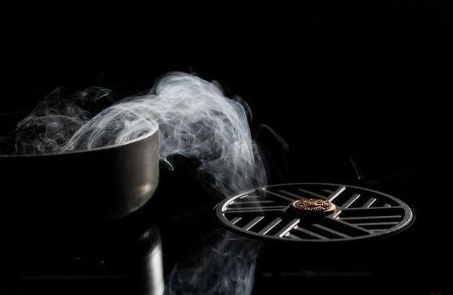 Credit: Bertazzoni Front view of a downdraft induction cooktop sucking fumes from a pot cooking on it