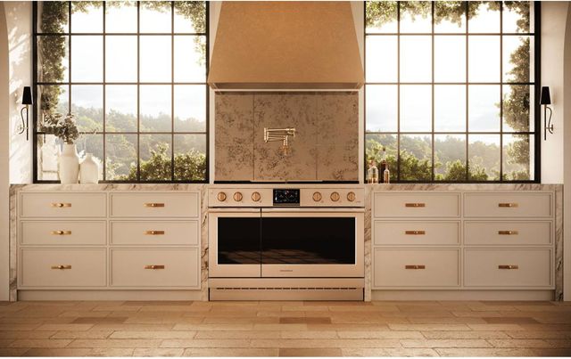 Front view of a modern kitchen with Monogram appliances including a range and a gold Monogram range hood