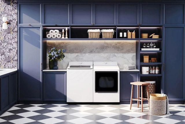 Front view of a modern laundry room with blue cabinets and a white LG top load washer and dryer