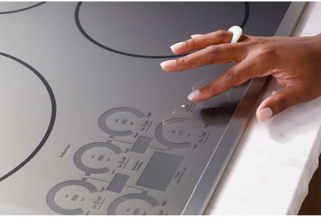 Close view of a person touching the touch controls on a Cafe 36 in induction cooktop