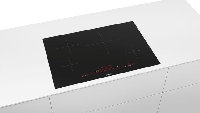 front view of a black bosch induction cooktop built into white cabinetry on a white background