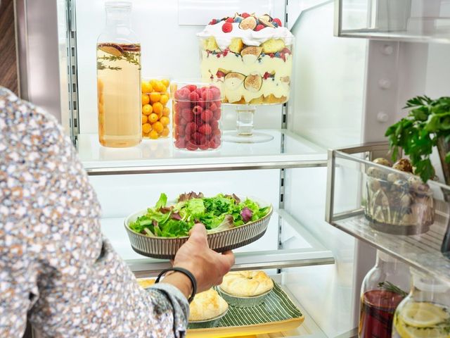 Close view of a woman placing a salad into a Sub-Zero refrigerator