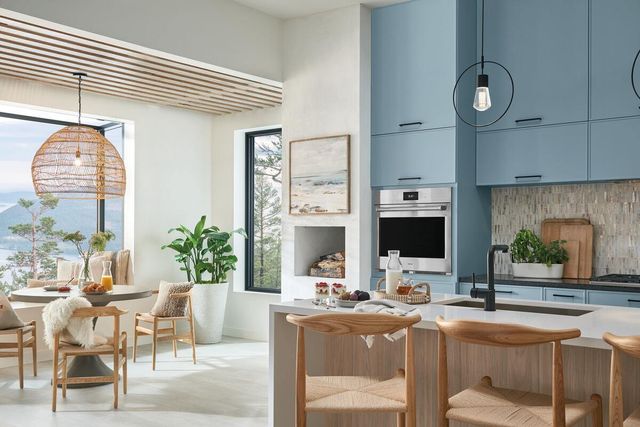 Front view of a modern boho kitchen with white walls, light blue cabinetry, and a Wolf E series wall oven