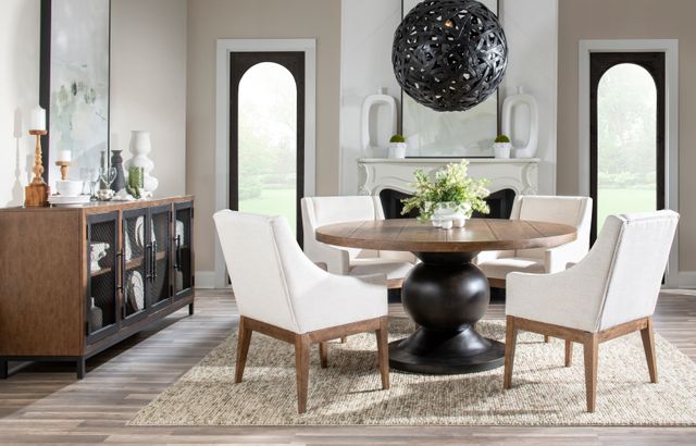 side view of a modern dining room with white walls, a round wooden table with a black pedestal and white chairs around it, with a wooden and black two-tone sideboard on the left 