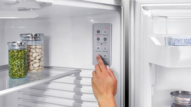 close view of a hand reaching into a fisher and paykel refrigerator to adjust the control panel