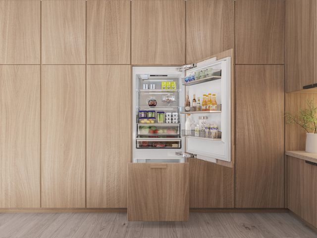 Front view of a modern wall of light wood cabinetry with a Thor Bottom freezer refrigerator with the door opened and freezer pulled out.