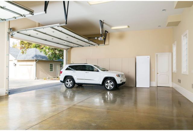Front view of a modern finished garage with a white car and white GE upright freezer