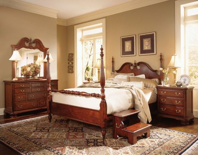 Front view of a traditional style bedroom with an ornate wooden poster bed and matching bedroom furniture