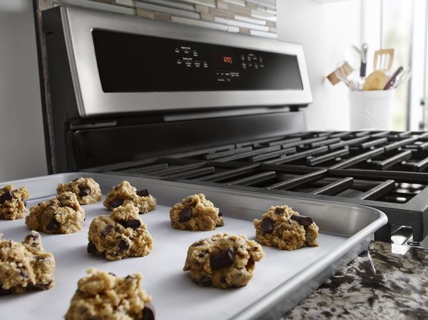 A person baking in a double oven electric range A person baking in a double oven electric range