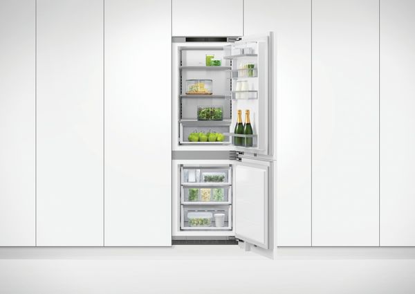 front view of a narrow bottom freezer built into a white panel wall