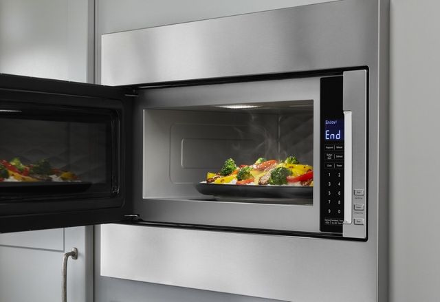 close view of an opened built-in microwave with a dish of veggies steaming inside